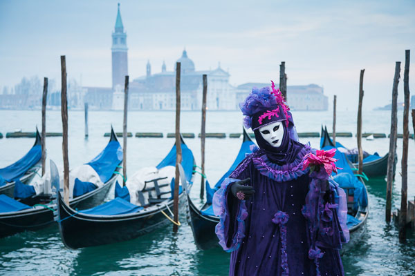 Costumed person in front of gondolas, Venice, Italy Costumed person in front of gondolas, Venice, Italy